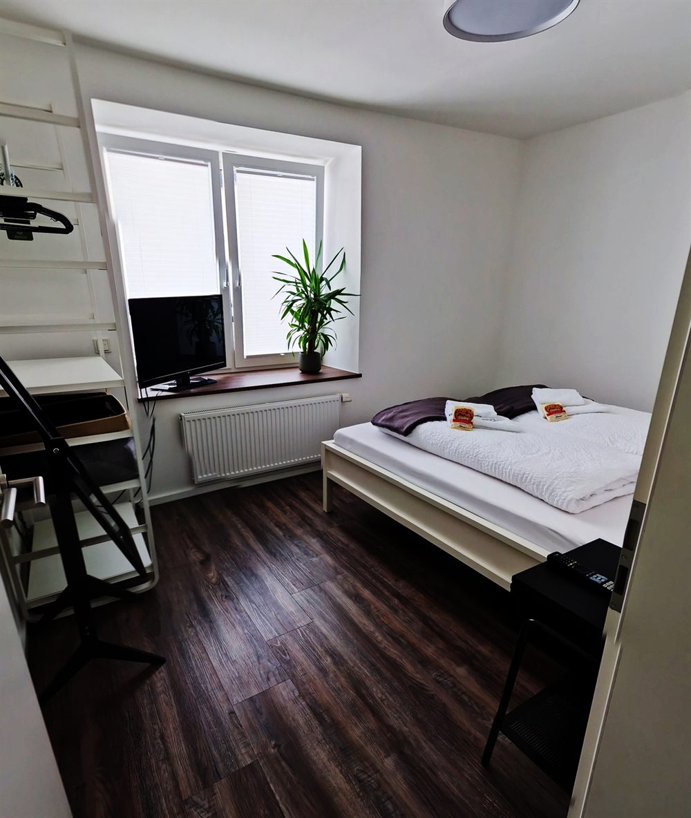 Schlafzimmer mit Doppelbett, Fernseher und offenem Kleiderregal