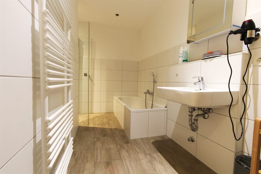 Helles Badezimmer mit Dusche, Waschbecken und Handtuchheizkörper