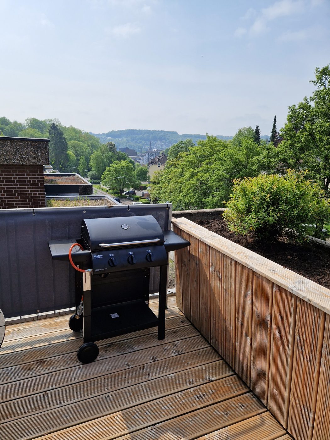 Gasgrill auf der Holzterrasse mit Blick über die bewaldeten Hügel