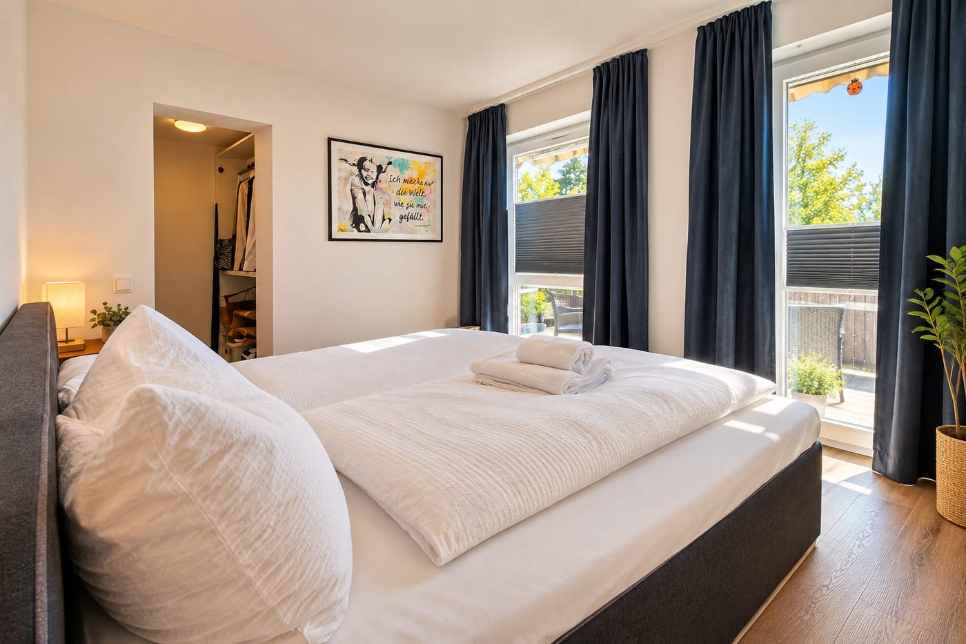 Schlafzimmer mit Boxspringbett, offener Ankleide und Tür zur Terrasse