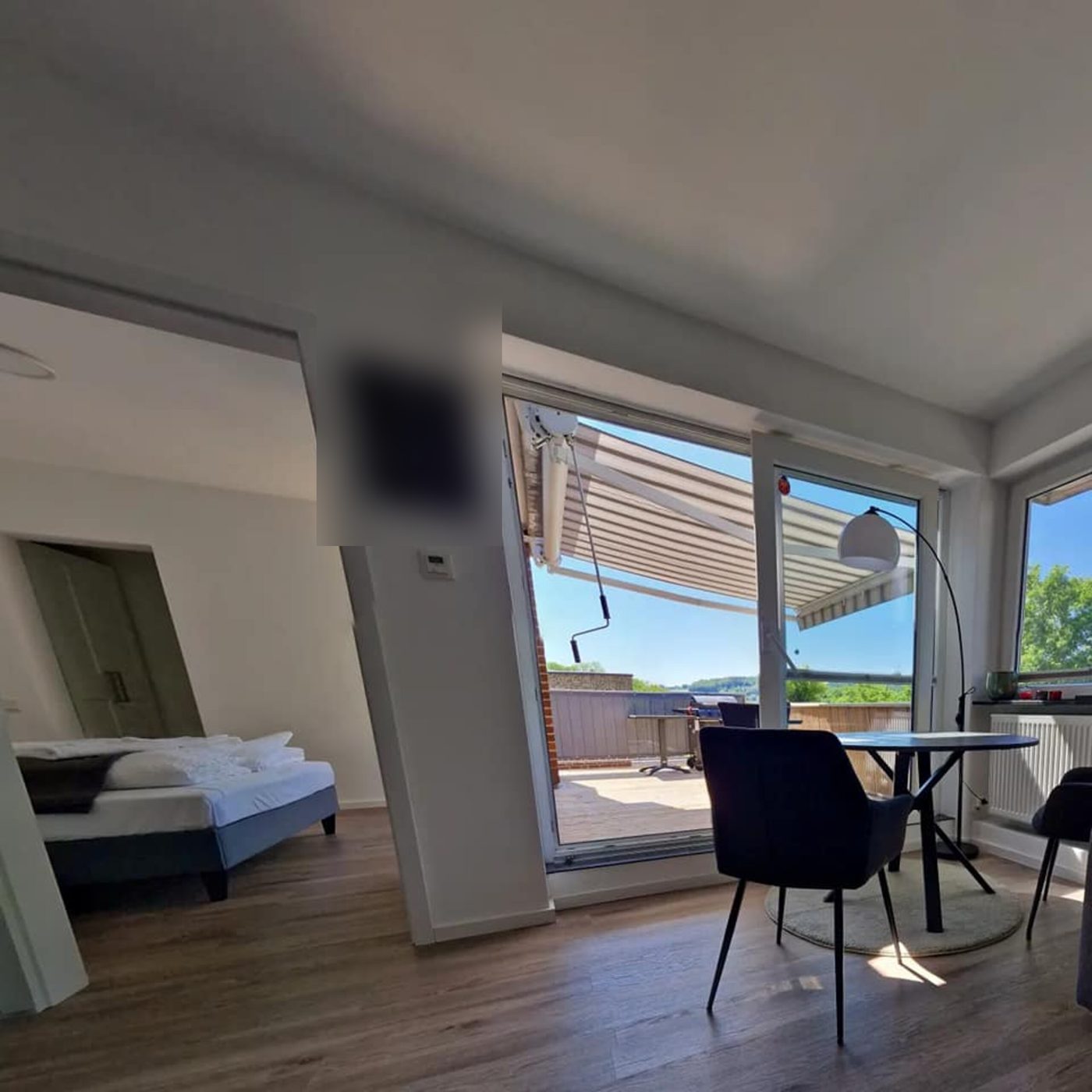 Wohnraum mit Blick durch die offene Tür ins Schlafzimmer und hinaus zur Terrasse
